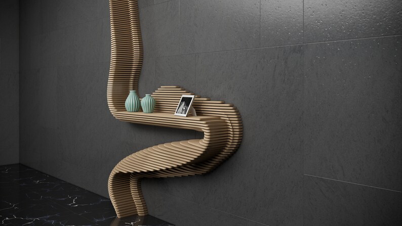 May include: A wooden shelf unit with a unique, curved design. The shelf is made of thin, layered wood and has a light brown finish. It features two small, teal vases and a framed photo.