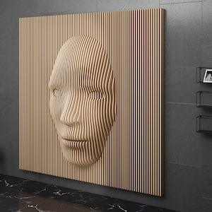 May include: A wooden wall sculpture of a face, made of thin strips of wood, with a 3D effect. The sculpture is mounted on a gray wall in a modern interior.