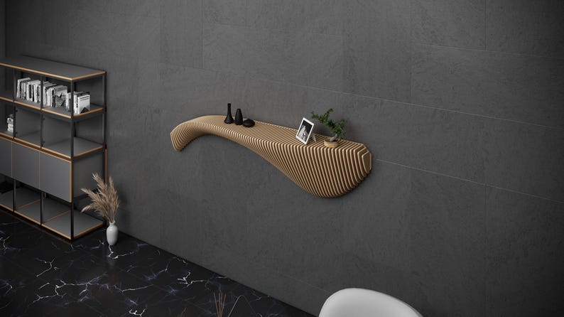 May include: A modern, curved wooden wall shelf with a light wood finish. The shelf is mounted on a gray wall and has a small plant and a framed photo on it.