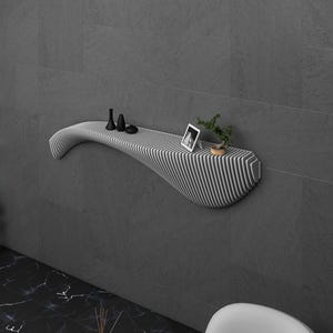 May include: A white, wavy, wall-mounted shelf with a black and white striped design. The shelf has a small plant, a picture frame, and three black decorative objects on it.