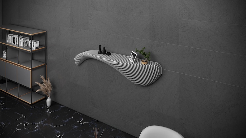 May include: A white, wavy, wall-mounted shelf with a black and white striped design. The shelf has a small plant, a picture frame, and three black decorative objects on it.