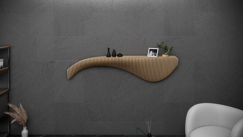 May include: A curved wooden shelf with a wavy design, mounted on a gray wall. The shelf has a small black vase, a black and white photo, and a small potted plant on top.