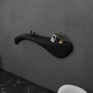 May include: A black, wavy, wall-mounted shelf with a small potted plant, a picture frame, and three small decorative objects on top.