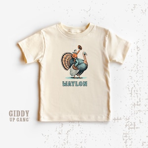 Cowboy Riding Turkey Kids Shirt: Custom Text Thanksgiving Graphic Tee ( GF6814 )
