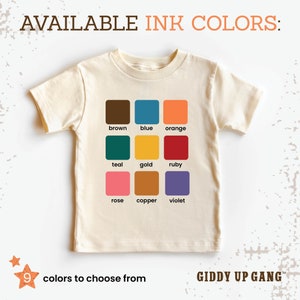 May include: A white t-shirt with a color chart showing nine different ink colors: brown, blue, orange, teal, gold, ruby, rose, copper, and violet. The text "AVAILABLE INK COLORS:" is at the top of the chart. The text "9 colors to choose from" is at the bottom left of the chart. The text "GIDDY UP GANG&trade;" is at the bottom right of the chart.
