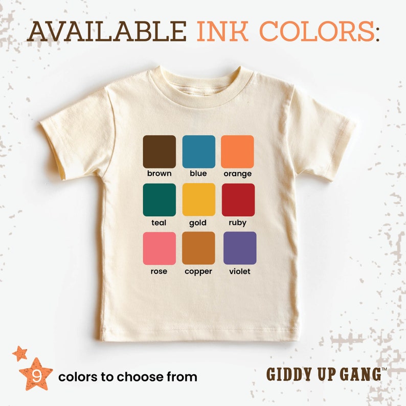 May include: A white t-shirt with a color chart showing nine different ink colors: brown, blue, orange, teal, gold, ruby, rose, copper, and violet. The text "AVAILABLE INK COLORS:" is at the top of the chart. The text "9 colors to choose from" is at the bottom left of the chart. The text "GIDDY UP GANG&trade;" is at the bottom right of the chart.