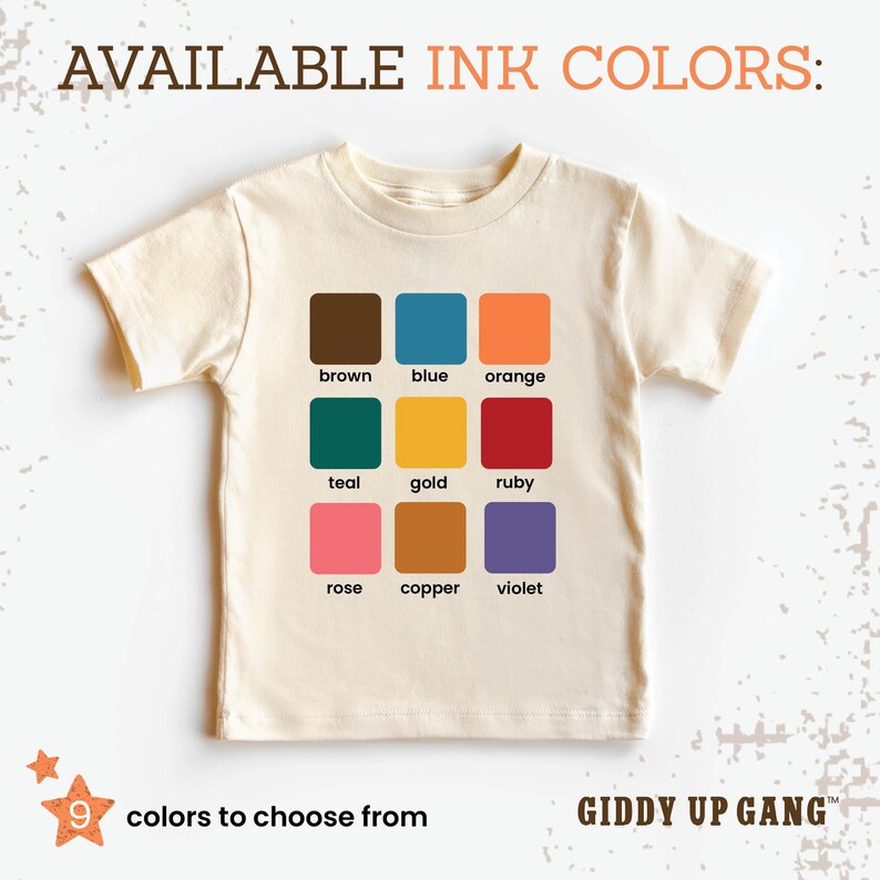 May include: A beige t-shirt with a color chart showing nine different ink colors: brown, blue, orange, teal, gold, ruby, rose, copper, and violet. The text "AVAILABLE INK COLORS:" is at the top of the chart. The text "9 colors to choose from" is at the bottom left of the chart. The text "GIDDY UP GANG&trade;" is at the bottom right of the chart.