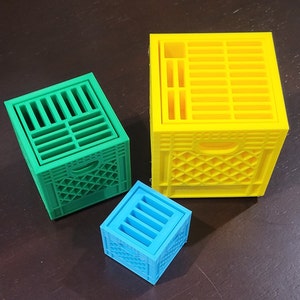 May include: Three miniature plastic crates in different sizes. The largest crate is yellow, the medium crate is green, and the smallest crate is blue.