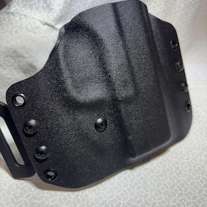 May include: Black plastic holster with multiple screw holes and a belt loop.