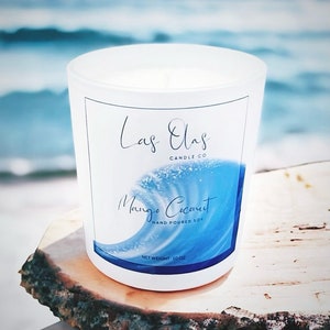 May include: White frosted glass candle jar with a blue wave design and the text "Las Olas Candle Co. Mango Coconut Hand Poured Soy Net Weight 10 oz."