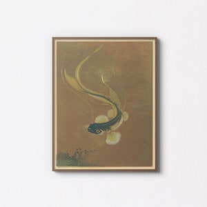 Può includere: Una stampa artistica incorniciata con un'illustrazione stilizzata di un pesce. Il pesce ha un corpo scuro, pinne gialle e una lunga coda fluente. Lo sfondo è di un caldo colore dorato.