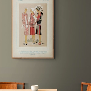 Pode incluir: Uma ilustra&ccedil;&atilde;o de moda vintage de tr&ecirc;s mulheres vestindo vestidos com padr&otilde;es geom&eacute;tricos. A ilustra&ccedil;&atilde;o est&aacute; emoldurada em uma moldura de madeira e tem texto em franc&ecirc;s.