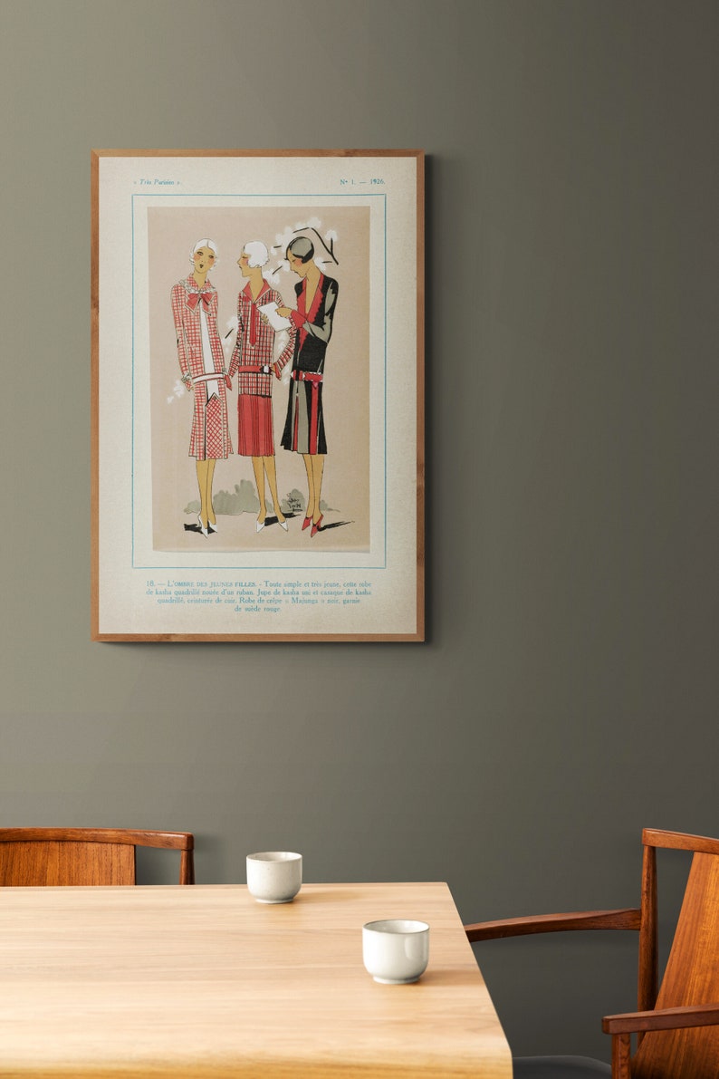 Pode incluir: Uma ilustra&ccedil;&atilde;o de moda vintage de tr&ecirc;s mulheres vestindo vestidos com padr&otilde;es geom&eacute;tricos. A ilustra&ccedil;&atilde;o est&aacute; emoldurada em uma moldura de madeira e tem texto em franc&ecirc;s.