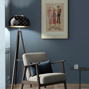 Pode incluir: Um candeeiro de ch&atilde;o geom&eacute;trico preto e dourado com uma base de trip&eacute;, uma poltrona bege com um almofada azul escuro e uma mesa auxiliar preta com um copo em cima. A parede &eacute; de cor azul escura e uma ilustra&ccedil;&atilde;o vintage emoldurada de tr&ecirc;s mulheres em vestidos est&aacute; pendurada na parede.