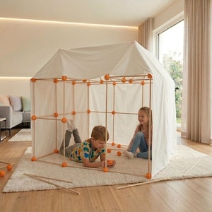 Könnte beinhalten: Ein Kinderspielzelt aus Holzdübeln und orangefarbenen Verbindern, bedeckt mit weißem Stoff. Zwei Kinder spielen in dem Zelt auf einem weißen Teppich. Das Zelt ist drinnen aufgebaut.