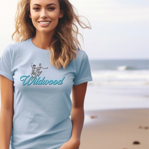 May include: A light blue t-shirt with a vintage graphic of two people jumping in the air. The graphic is in blue and white and says "Wildwood, New Jersey" in a cursive font.