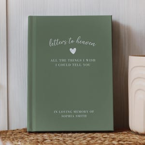 May include: A sage green journal with the words "letters to heaven" in script, a heart symbol, and the text "ALL THE THINGS I WISH I COULD TELL YOU." The bottom reads "IN LOVING MEMORY OF SOPHIA SMITH."