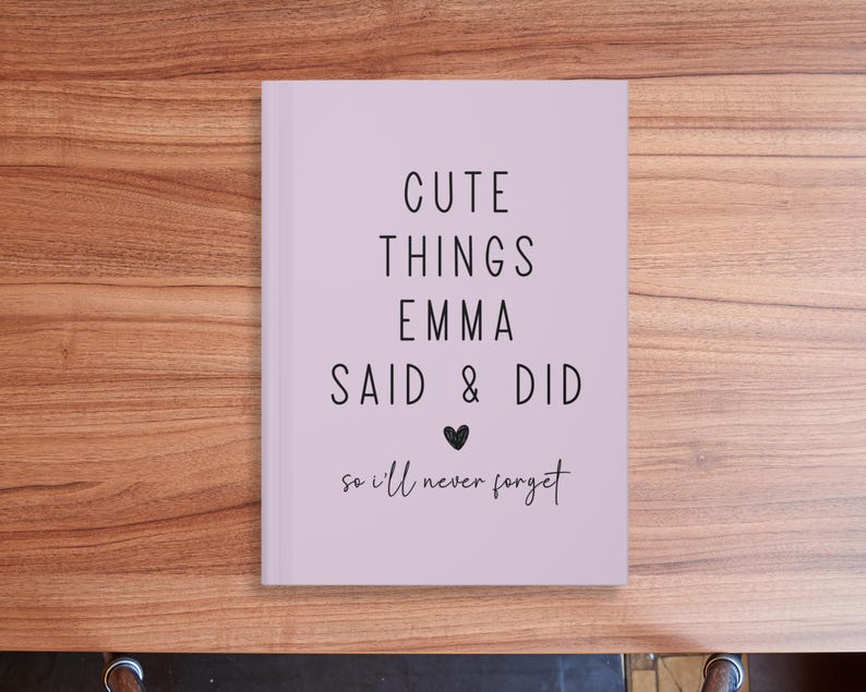 May include: A lavender-colored journal with the text "Cute Things Emma Said & Did so I'll never forget" in black lettering. A small heart symbol is between "Said" and "Did".