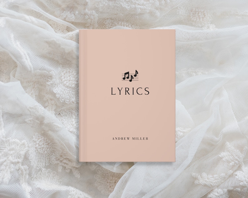 May include: A pink notebook with the word "LYRICS" printed in black on the front cover. The cover also features a black musical note symbol. The author's name, "ANDREW MILLER", is printed in black at the bottom of the cover.