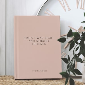 May include: A blush-colored book with the text "TIMES I WAS RIGHT AND NOBODY LISTENED" in black. The author's name, "BY EMILY JONES," is printed below. The book is set against a neutral background with a clock and greenery.