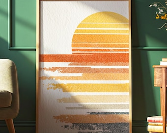 May include: Framed art print with a sunset design. The artwork shows a yellow and orange sun setting over horizontal bands of orange, yellow, and grey hues. The print is encased in a light brown wooden frame.