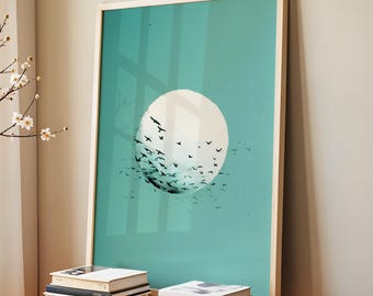 May include: A framed art print featuring a white circle with black birds against a teal background. The artwork is in a light wood frame and leans against a wall. Several books are stacked on a red table in front of the artwork.
