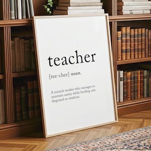 May include: A framed white print with the word "teacher" in black, along with a definition. The definition reads: "A miracle worker who manages to maintain sanity while herding cats disguised as students."
