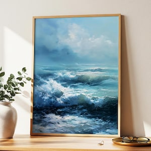 May include: A framed artwork of the sea, presented in a wooden frame. The painting shows a seascape with breaking waves in blue and white hues beneath a cloudy sky. The artwork is displayed on a wooden surface.