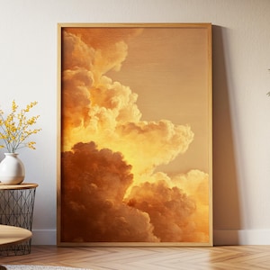 May include: A framed art print featuring a dramatic depiction of golden clouds. The artwork showcases a warm color palette of oranges and yellows, with a wooden frame. The print is displayed indoors, leaning against a white wall.