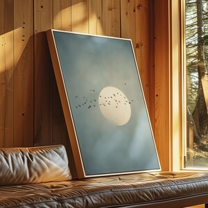 Pu&ograve; includere: Una stampa artistica incorniciata con un paesaggio sereno con un grande sole giallo pallido e uno stormo di uccelli in volo contro un cielo blu-verde attenuato. L'opera d'arte &egrave; esposta su una parete di legno, vicino a una finestra.