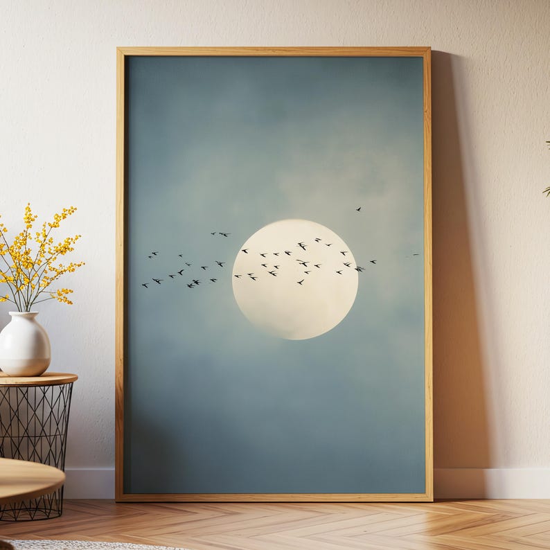 Pu&ograve; includere: Una stampa artistica incorniciata con un grande cerchio bianco brillante contro un cielo blu tenue. Uccelli silhouette volano davanti al cerchio. La cornice &egrave; di colore marrone chiaro.