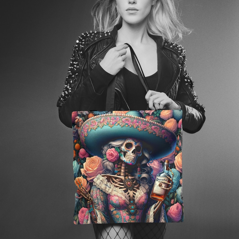 May include: A tote bag with a colorful illustration of a skeleton wearing a sombrero and holding a bottle of tequila. The skeleton is surrounded by flowers and has a skull face with a painted design.