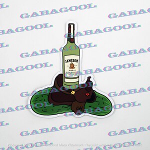 May include: A sticker featuring a green Jameson Irish Whiskey bottle atop a brown saddle, resting on a green pickle. The sticker has a white border and the text "JAMESON" is visible on the bottle.