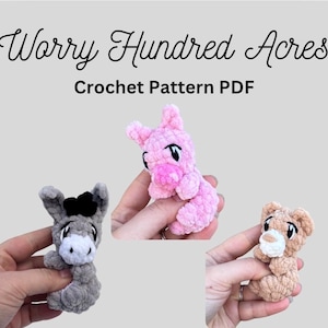 Può includere: Modello PDF all'uncinetto con tre piccoli animali di peluche: un asino grigio, un maiale rosa e un orso marrone. Il testo "Worry Hundred Acres" e "Crochet Pattern PDF" sono visualizzati in alto.