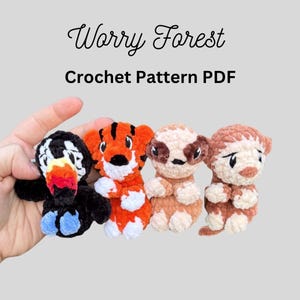 May include: A collection of four crocheted animal figures: a toucan, a tiger, a sloth, and a monkey. The toucan is black with a white and red beak, the tiger is orange with black stripes, the sloth is tan, and the monkey is brown. The text "Worry Forest Crochet Pattern PDF" is above the figures.