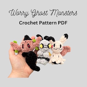Peut inclure: Trois petites figurines en crochet étiquetées Worry Ghost Monsters Crochet Pattern PDF. La figurine de gauche est rose poudré avec des détails noirs et rouges, celle du centre est grise avec des yeux jaunes, et celle de droite est crème.
