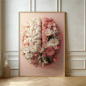 Könnte beinhalten: Gerahmter Kunstdruck mit einem stilisierten Gehirn-Design. Die linke Gehirnhälfte ist weiß, die rechte rosa, beide verziert mit rosa und weißen Blumen. Das Kunstwerk ist vor einem zartrosa Hintergrund platziert.