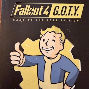 May include: A black Fallout 4 G.O.T.Y. Game of the Year Edition game case featuring the Vault Boy character giving a thumbs up. The cover includes award logos for DICE, BAFTA Games, and E3, with yellow text and a yellow gear-shaped background.