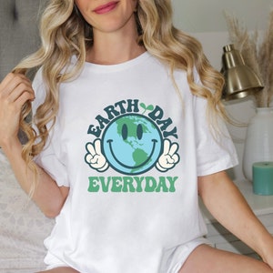 May include: White t-shirt with a green and blue graphic of a smiling Earth with the text "Earth Day Everyday" in green letters.
