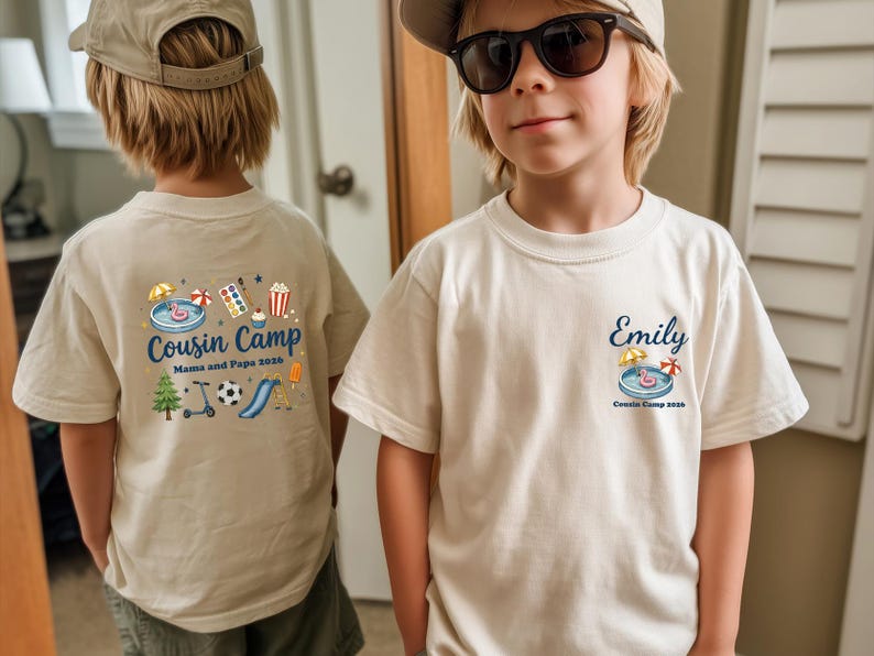 Pu&ograve; includere: Una t-shirt beige con stampa grafica. La parte anteriore mostra il nome Emily sopra una piccola illustrazione di una piscina e il testo Cousin Camp 2026. Il retro presenta una grafica pi&ugrave; grande con il testo Cousin Camp Mama and Papa 2026.