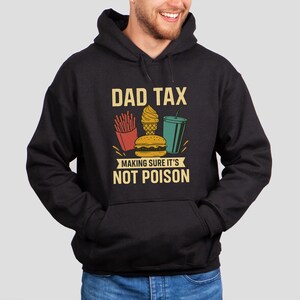 May include: Black hoodie featuring the text "DAD TAX" and a graphic of fast food: fries, a burger, ice cream, and a drink. The text "MAKING SURE IT'S NOT POISON" is below the graphic, in a yellow font.