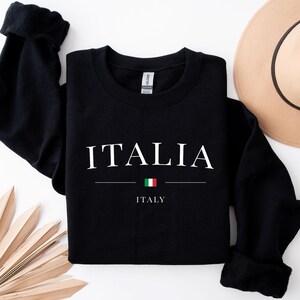 May include: Black sweatshirt with the word "ITALIA" in white text and the Italian flag underneath. The text "ITALY" is written in white below the flag.