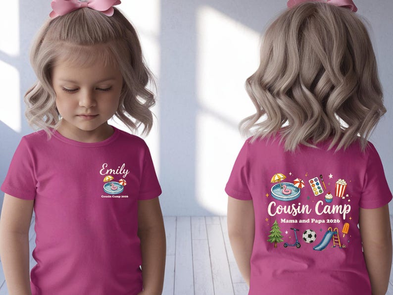 Pu&ograve; includere: Una t-shirt a maniche corte rosa acceso con una piccola grafica sul petto con il nome Emily e il testo Cousin Camp 2026. Il retro mostra una grafica pi&ugrave; grande con il testo Cousin Camp Mama and Papa 2026 e varie icone colorate.