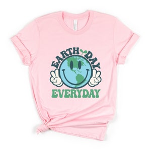 May include: Pink t-shirt with a green, blue, and white smiley face graphic of the Earth with the text "Earth Day Everyday" in green and blue.
