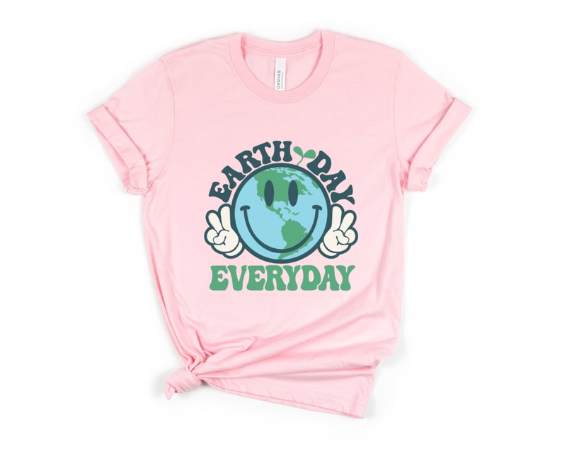 May include: Pink t-shirt with a green, blue, and white smiley face graphic of the Earth with the text "Earth Day Everyday" in green and blue.