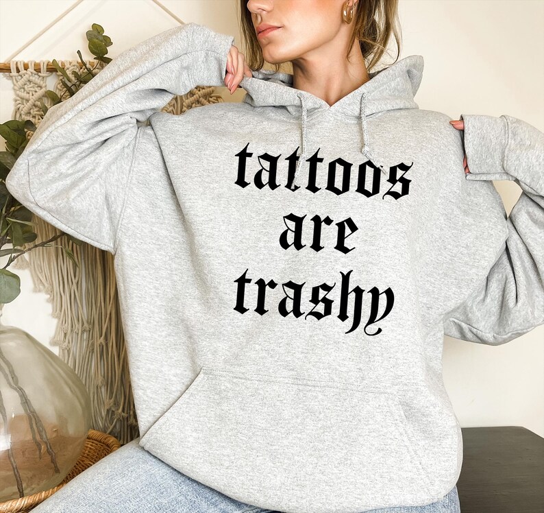 May include: Gray hooded sweatshirt with the text "tattoos are trashy" printed in black gothic font.