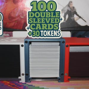 May include: Three card storage boxes in white, blue, and red. Each box holds cards, with labels indicating capacity: 100 double-sleeved cards, 100 double-sleeved cards + 30 tokens, and 100 single-sleeved cards + 40 tokens.