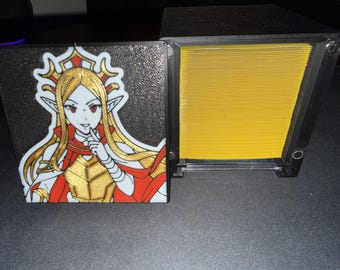May include: A black card holder with a hinged lid, featuring a colorful anime-style illustration of a woman with long blonde hair, red eyes, and a red and gold outfit. The holder is open, revealing a stack of yellow cards.