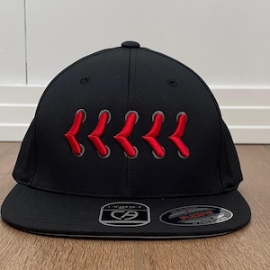 May include: Black baseball cap with a curved peak. The cap has a series of red embroidered chevrons across the front. The cap has a structured fit and a Flexfit brand label.