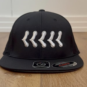 May include: Black baseball cap with a curved peak. The cap has five white, stylized chevrons embroidered across the front. The Flexfit brand logo is visible on the peak.